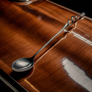 "Bar spoon with a twisted handle placed on a polished wooden bar counter, realistic and highly detailed,